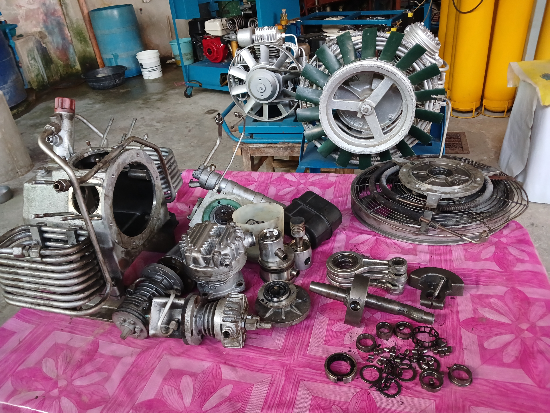 Full compressor teardown with rebuilt units in background