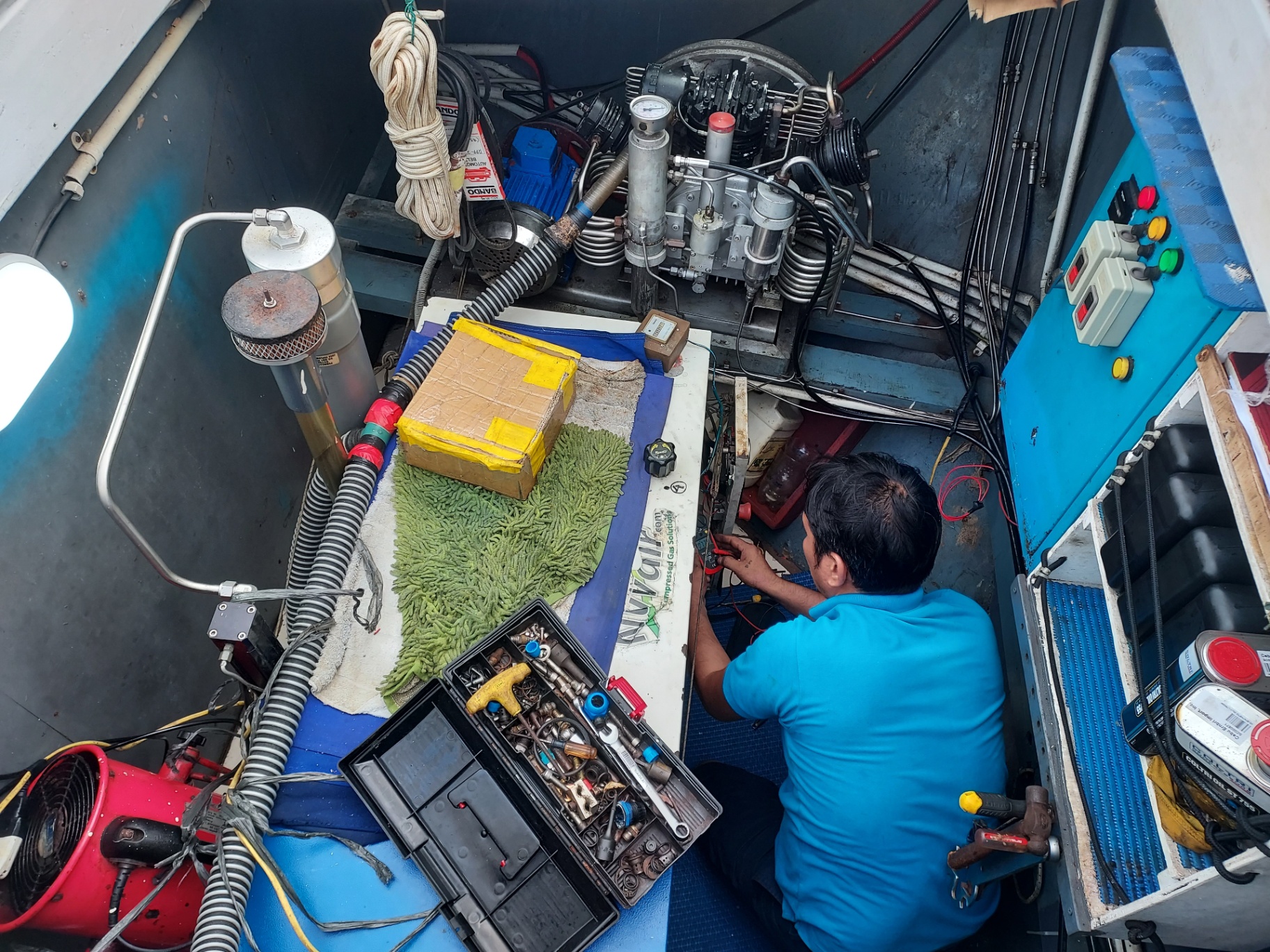 Technician servicing an onboard compressor in the vessel's compressor room